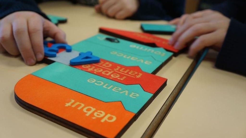 photographie de mains d'enfants tenant des nombres et des bulles de programmation en bois